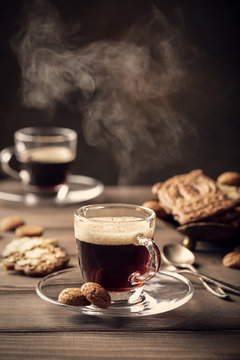Fototapeta Steaming coffee cup on old wooden background with copy space. Retro style toned dark photography.