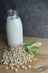 Pouring bio soy milk on rustic wood dark background