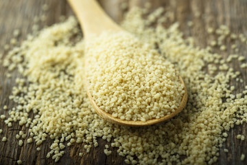 Dry couscous grain in the wooden spoon