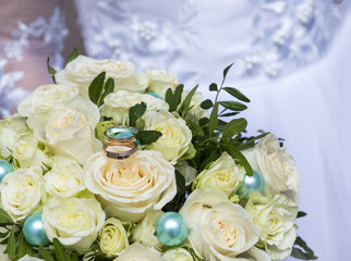 wedding bouquet of a bride from white roses with gold wedding rings