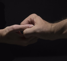 close up female and male hands holding on black background