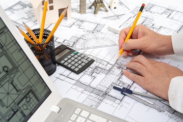 The hand of a male architect drawing a design using a pencil.