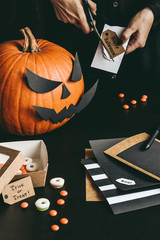 Halloween preparation. Hands making halloween decoration using craft paper