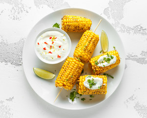 Grilled sweet corn with white mexican sauce, chilli and lime. healthy summer food