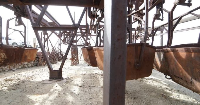 Second station of old Cable Car Chilecito-La Mejicana mine. Detail of iron wagons. Camera moves sideways showing the linear disposition of hanging wagons, iron structure appears in front the scene