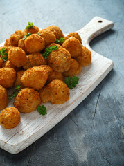 Homemade Breaded Garlic Mushrooms with sour cream and parsley on white wooden board