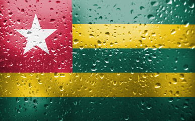 Texture of Togo  flag on the glass with drops of rain.