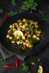 Fried kale and potato gnocci with chilie, peccorino cheese and lemon wedges in black plate. Italian food