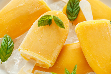 Popsicles, ice lollies on stick with sweet orange juice in white plate with ice