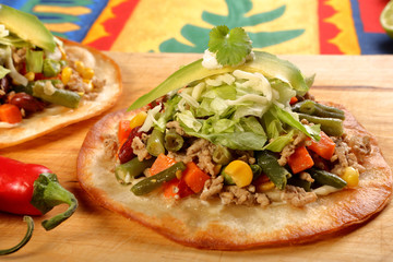 Crunchy beef tostada stack, typical mexican food, made with crispy fried corn tortillas with guacamole, cheese, sour cream and salsa