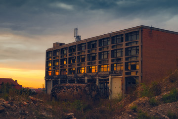 sunset reflected in the broken windows of the abandoned industrial building