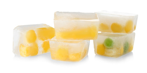 Corn grains and green peas in ice cubes on white background. Frozen vegetables