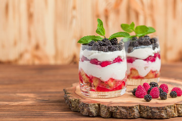 Trifle close up photography with fresh multi layered dessert with dairy and ripe raspberries and blackberries.