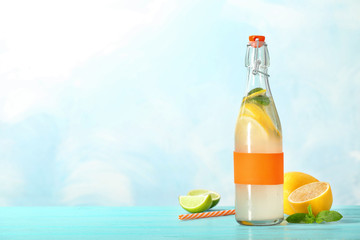 Bottle with natural lemonade on table against color background