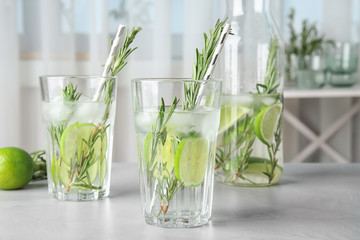 Tasty refreshing cocktail with rosemary and lime on table