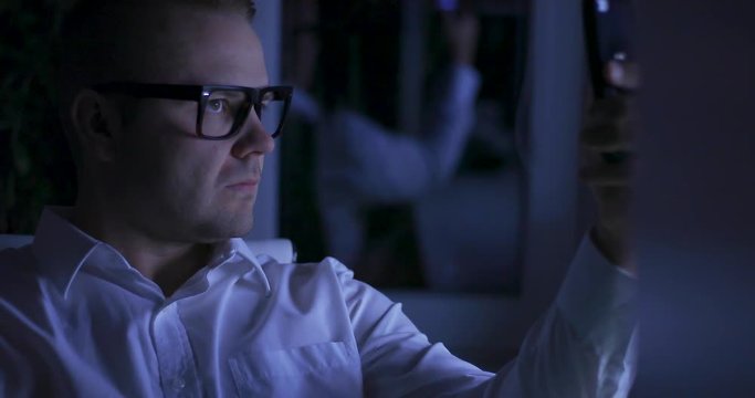 Unfaithful businessman in night office making selfie to social media