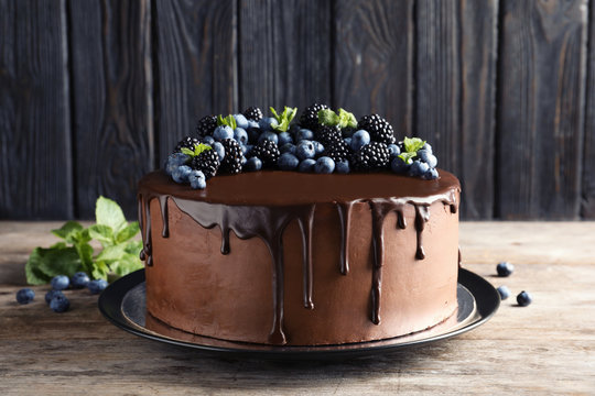 Fresh delicious homemade chocolate cake with berries on table against wooden background