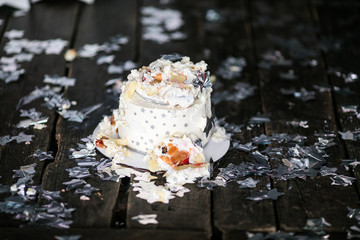 Smashed first birthday white cake with stars and one candle for little baby boy and decorations. Black background