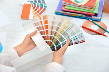 Woman with paint color palette samples at table, closeup