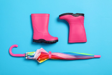 Flat lay composition with umbrella and rubber boots on color background