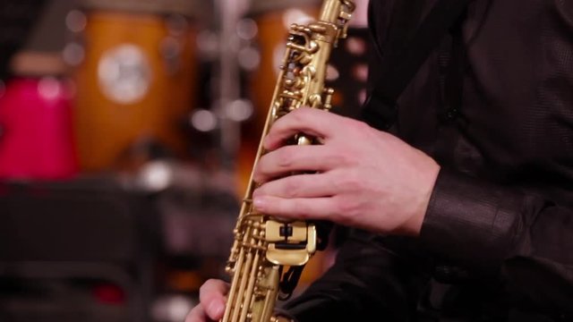 A man in a black shirt plays jazz music. Close-up of the hands of a saxophonist on a soprano saxophone. Loop.