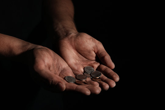 Poor man with coins on dark background, closeup