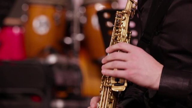 A man in a black shirt plays jazz music. Close-up of the hands of a saxophonist on a soprano saxophone. Loop.