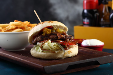 hamburger with beef on it and fried potatoes on a wooden background
