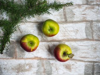 New Year greeting card, apples, a sprig of larch on a background imitating a bricklaying