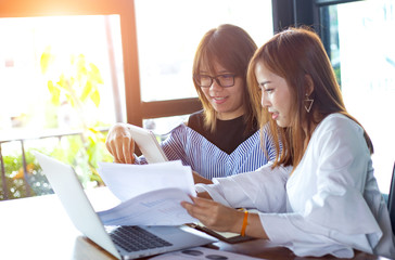 Smiling Asian businesswoman holding tablet at desk in creative office