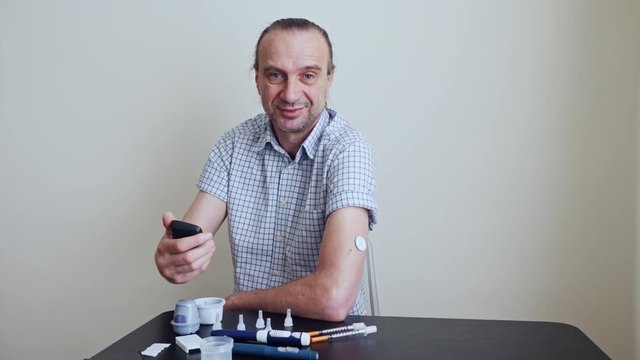 A man brings to the hand the reading device to the sensor for measuring glucose