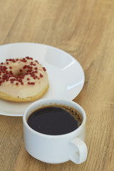 Donut with black coffee on wooden
