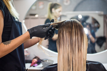 The hairdresser applies nutritious and healing components to damaged hair, applying botox to the...