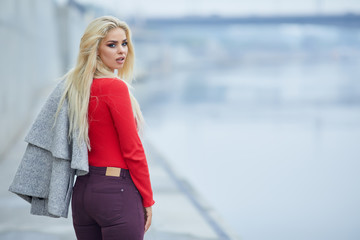 Gorgeous lady in red sweater poses before a river