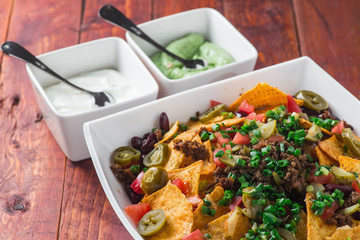 A plate of delicious nachos with jalapeno, beans and guacamole sauce