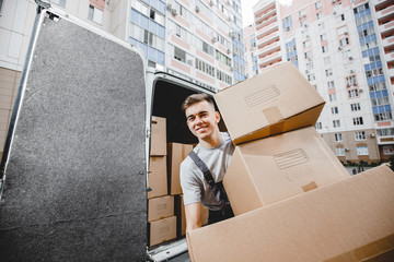 A young handsome smiling worker wearing uniform is unloading the