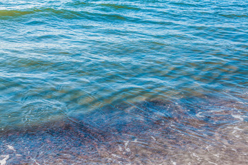 pure azure clear water with white foam on the sea on a sunny afternoon, blurry background