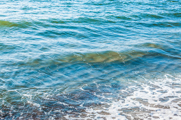 pure azure clear water with white foam on the sea on a sunny afternoon, blurry background