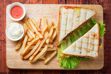 Club sandwich served with french fries on wooden backgorund