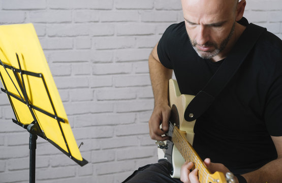 Man studying music with electric guitar at home