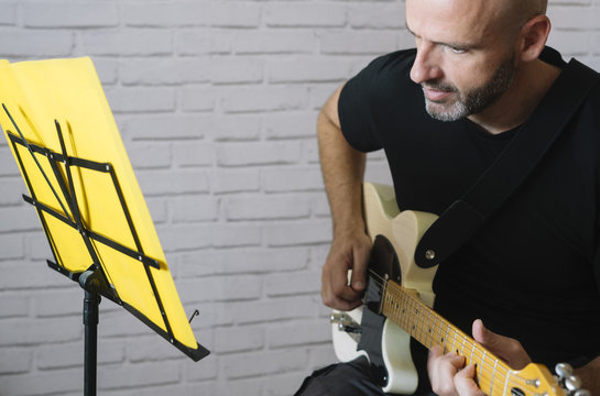 Man studying music with electric guitar at home