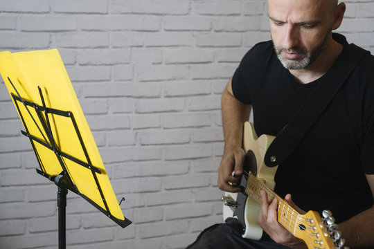 Man studying music with electric guitar at home