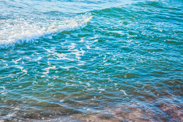 pure azure clear water with white foam on the sea on a sunny afternoon, blurry background