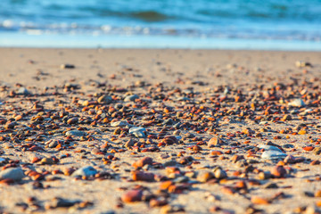 multicolored pebbles on a sea sandy beach on a sunny afternoon close up blurred background