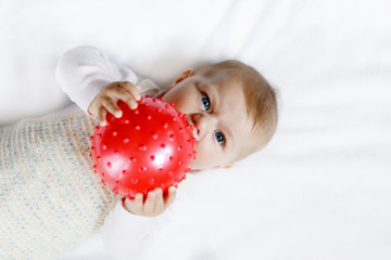 Cute baby playing with red gum ball. New born child, little girl having fun, grabbing and crawling....