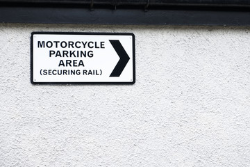 Motorcycle parking area securing rail sign on white wall