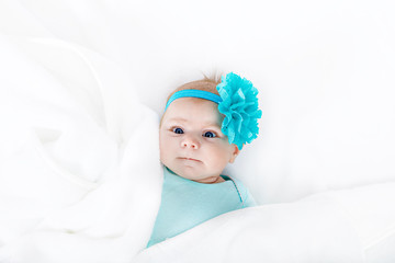 Cute adorable newborn baby in white bed and wrapped in blanket. New born child, little girl looking surprised at the camera. Family, new life, childhood, beginning concept