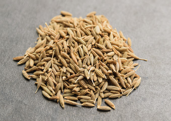 Pile of cumin seeds on dark background. Macro with shallow depth of field.