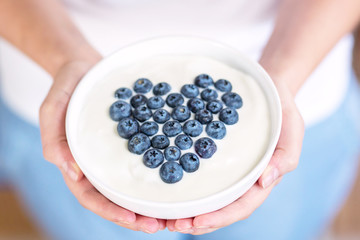 Schale mit Joghurt und frischen Blaubeeren zu Herz geformt