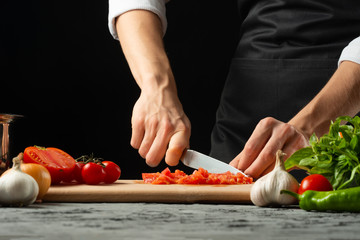 The chef cuts and tastes tomatoes, preparing an Italian tomato sauce for macaroni.pizza. The concept of the Italian cooking recipe
